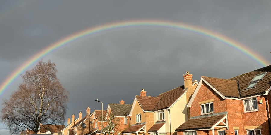 A rainbow over the rooves of houses in a modern estate.